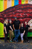 five people standing together and laughing, all wearing black shirts that say fruition chocolate works on the front