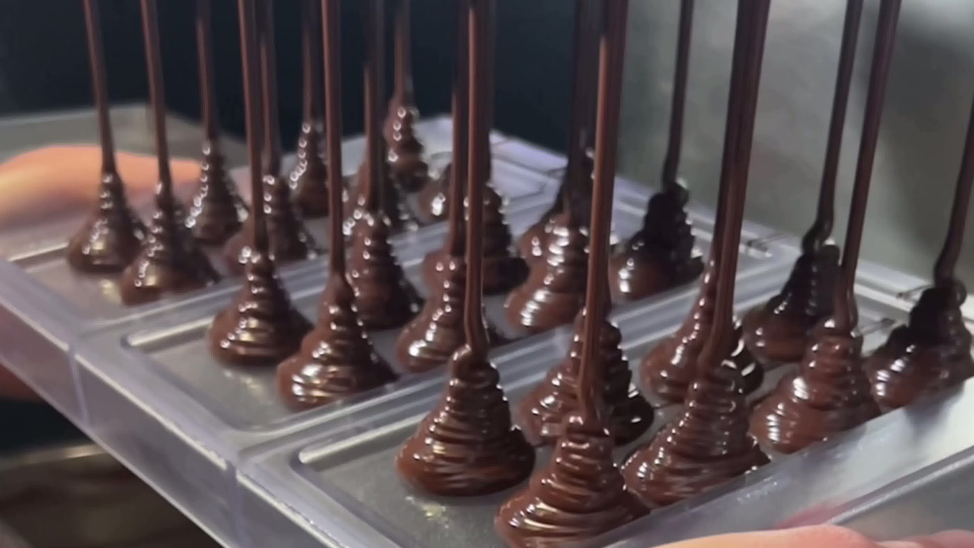 Chocolate being dripped onto a tray from a piping bag